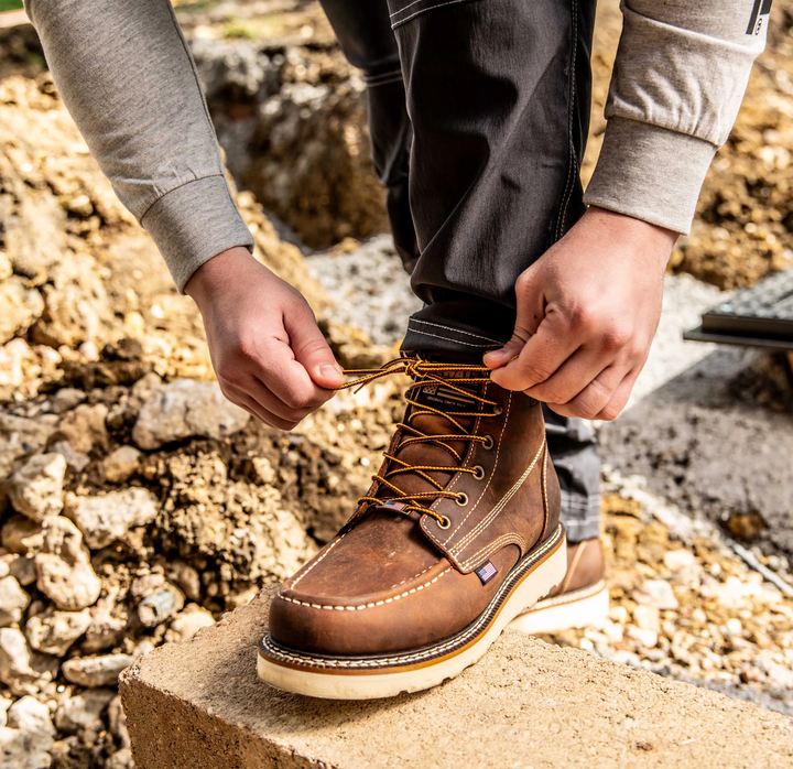 DEWALT Weatherby Men's Made in USA Pro Comfort, Full Grain Leather, Moc Toe Work Boot - 3/4 Front Left View With Model Tying Laces